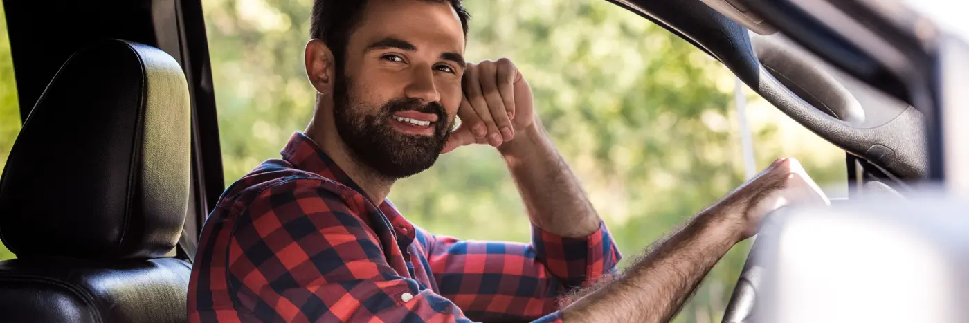 Mand i skovmandsskjorte på førersædet af en bil
