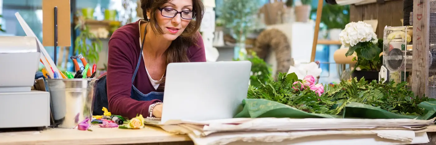 Kvinde foran pc i blomsterbutik