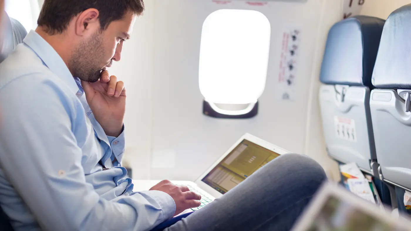 Forretningsmand med bærbar computer i flyvemaskine