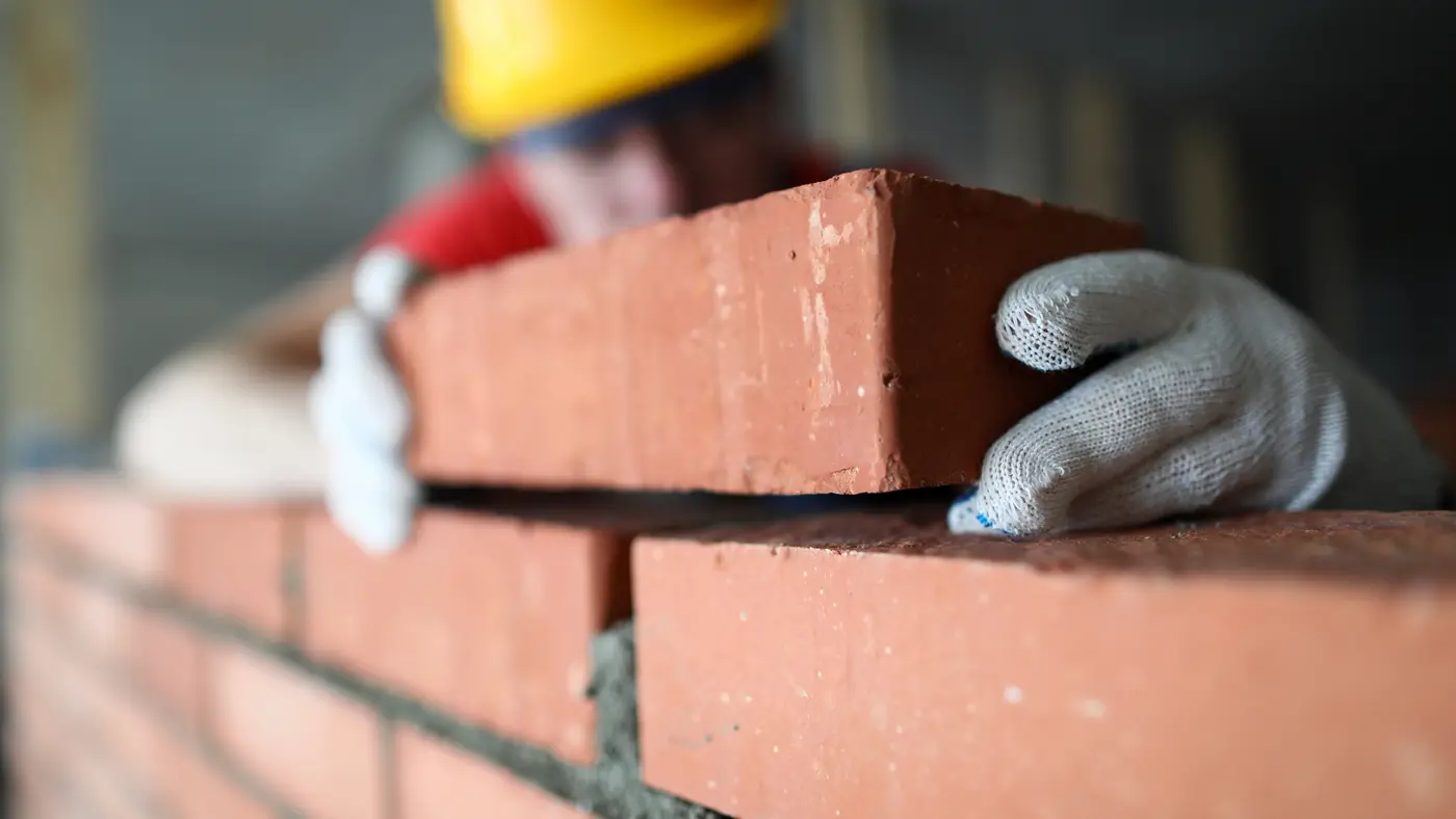 Murer ved at bygge mur af røde mursten