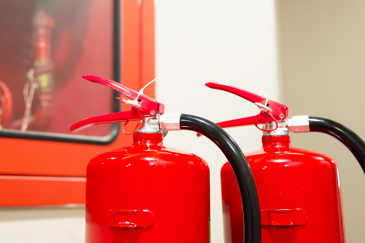 Røde brandslukkere foran brandskab